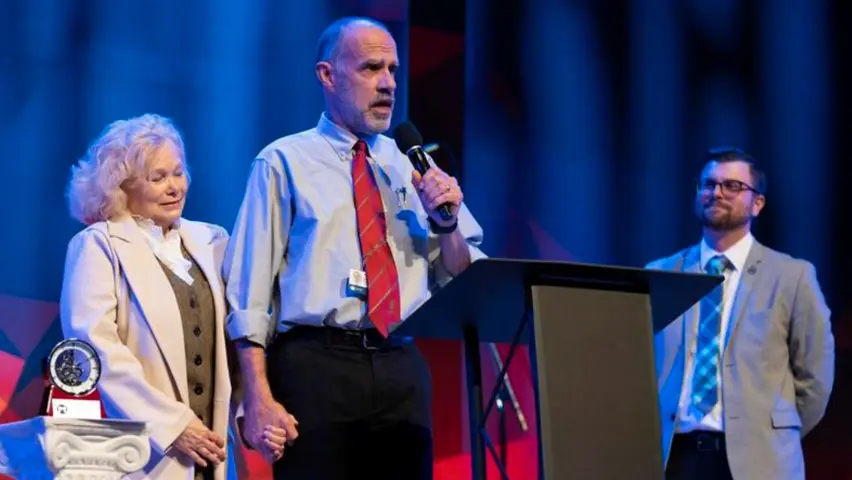 Dr. Gerald Peterman giving his 2023 Faculty Citation Award speech, his wife Marjory standing next to him